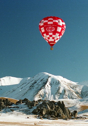Kit-Kat brand hot air balloon over snowy mountains